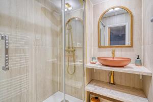 a bathroom with a sink and a glass shower at Eden Suite Paris la Defense in Courbevoie
