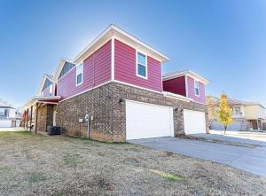 a red house with two white garage doors at Modern Home 10 minutes from Dickson St & U of A in Fayetteville