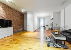 sala de estar con sofá negro y pared de ladrillo en Bright & Cozy 3BD Apartment In Mid West, en Nueva York