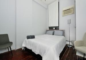 1 dormitorio blanco con 1 cama y 1 silla en Bright & Cozy 3BD Apartment In Mid West, en Nueva York