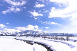 un fiume nella neve con montagne sullo sfondo di Sakadojo a Minami Uonuma