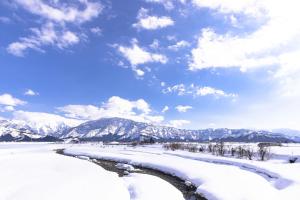 un río en la nieve con montañas en el fondo en Sakadojo, en Minami Uonuma
