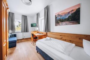 Cette chambre comprend un lit et un bureau. dans l'établissement Weidegg - Hotel Garni, à Garmisch-Partenkirchen