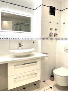 een witte badkamer met een wastafel en een toilet bij Luxus Maisonette Wohnung, Apartment am See, Wehome Komfort in Sankt Leon-Rot