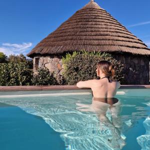 une femme debout dans l'eau dans une piscine dans l'établissement Is Cheas wine farm boutique hotel, à San Vero Milis
