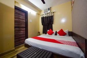 Un dormitorio con una cama con almohadas rojas y una ventana en OYO Hotel Vaishnavi en Kota