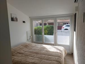 a bedroom with a bed and a large window at Le Bleu du Sud in Gruissan +8 photos