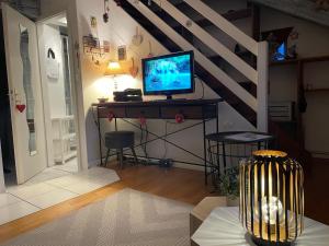 ein Wohnzimmer mit einem Schreibtisch und einem TV darauf in der Unterkunft Aux petits cœurs de COLMAR CENTRE WIFI in Colmar