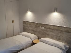 2 camas en una habitación con 2 luces en la pared en Hostal Ginebra, en Madrid