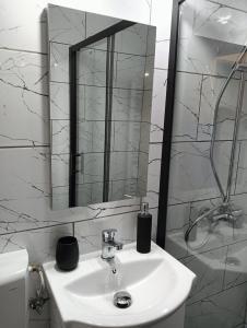 a white bathroom with a sink and a mirror at Apartament HD2 in Hunedoara