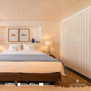 a bedroom with a large bed with two pictures on the wall at T2 Casa das Pereiras in Calheta de Nesquim