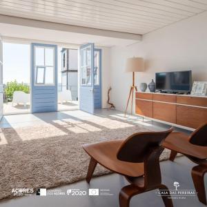 ein Wohnzimmer mit einer blauen Tür und einem TV in der Unterkunft T2 Casa das Pereiras in Calheta de Nesquim