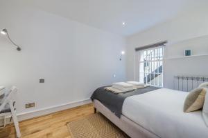 a white bedroom with a bed and a window at The Fairytale - Fitzrovia - by Frankie Says in London