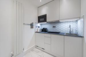 a white kitchen with white cabinets and a sink at The Fairytale - Fitzrovia - by Frankie Says in London