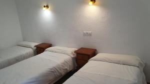 3 camas en una habitación con luces en la pared en Hostal Ginebra, en Madrid