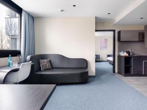 ein Wohnzimmer mit einem schwarzen Sofa und einem Tisch in der Unterkunft numa I Viktoria Apartments in München