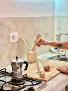 a person holding a wooden spoon on a cutting board in a kitchen at Boutique Apartments Ibiscus in Santa Maria