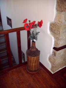 un vaso pieno di fiori rossi seduto su un pavimento di B&B Nonna Peppina a Mògoro