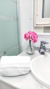 un jarrón de flores rosas sentado en el mostrador del baño en Hospedaje San Francisco, en Segovia