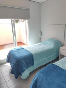 a bedroom with two beds and a large window at Departamento Céntrico Trelew in Trelew