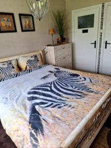 a bed with a zebra blanket on top of it at B&B de Vrijheid en de Ruimte in Steenbergen in Steenbergen