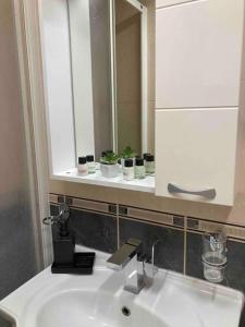 La salle de bains est pourvue d'un lavabo blanc et d'un miroir. dans l'établissement Calvin Apartment 9, à Ohrid