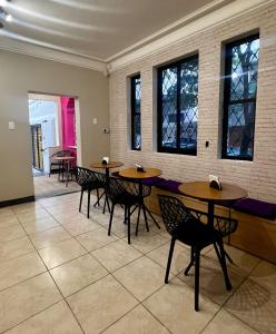 uma sala de jantar com mesas, cadeiras e janelas em Belô Hostel em Belo Horizonte