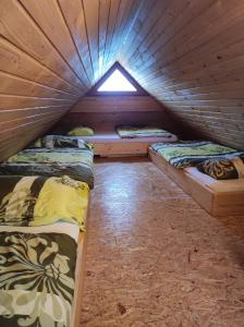 2 Betten in einem Holzzimmer mit Fenster in der Unterkunft Apartmaji Vrhovnik in Cerklje na Gorenjskem