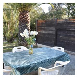 una mesa azul con sillas y un jarrón de flores en Le Mas de la Palmeraie - Mas 3 dans propriété privée au calme avec piscine et tennis, en Bormes-les-Mimosas