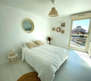 una camera da letto bianca con un letto grande e una finestra di Villa avec piscine d'intérieur “ Losalia “ a Talant