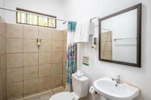 a bathroom with a toilet and a sink and a mirror at Jaco Lodge Quiet Place in Jacó