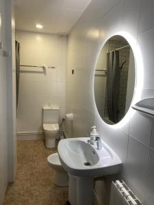 een badkamer met een wastafel, een toilet en een spiegel bij Hostal Carlos III in El Prat de Llobregat