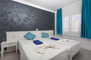 ein Schlafzimmer mit einem großen weißen Bett mit blauen Kissen in der Unterkunft FERRERA SUITES in Cala Ferrera