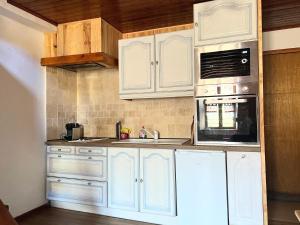 uma cozinha com armários brancos, um lavatório e um micro-ondas em T2 au charme authentique em Briançon