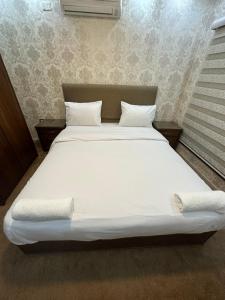 1 cama grande con sábanas y almohadas blancas en al-burj apart 7th circle en Amán