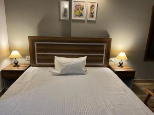 a bedroom with a large white bed with two lamps at Risals Home Stays in Greater Noida