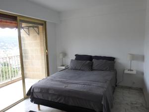 een bed in een slaapkamer met een groot raam bij Mont Joly YourHostHelper in Le Cannet