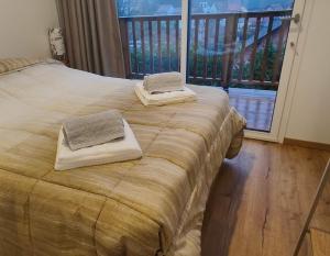 的住宿－Aux Sons des Cloches - Chalet avec Jacuzzi, Sauna et vue panoramique，一张带两张毛巾的床和一个阳台