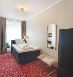 Habitación de hotel con cama y espejo en Top Hotel Krämer en Koblenz