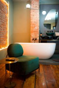 a bathroom with a bath tub and a green ottoman at World Studio Sibiu in Sibiu