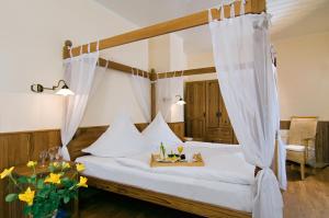 a bedroom with a canopy bed with a tray of food on it at Hotel Ekke Nekkepenn in Nebel