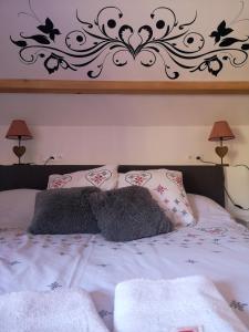una camera da letto con un letto con lenzuola bianche e opere d'arte alle pareti di La Fruitière d'Arith ad Arith