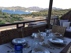 una mesa con platos y copas de vino en el balcón en Smeralda Residenza Di Charme, en Marina di Portisco