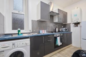 a kitchen with a sink and a washing machine at Large 4 bedroom flat, 5 mins to St James', parking in Elswick