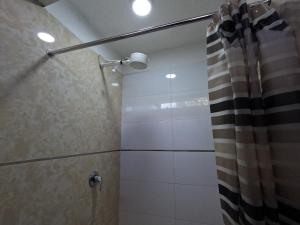 y baño con ducha y cortina de ducha. en Millpu Hostal, en Ayacucho
