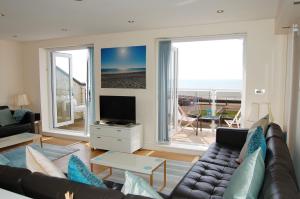 a living room with a couch and a view of the ocean at Sunset Bay Beach House in Tywyn in Tywyn