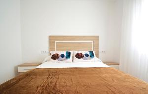 a bedroom with a large white bed with blue pillows at Apartamento con vistas en Playa de As Sinas in Villanueva de Arosa