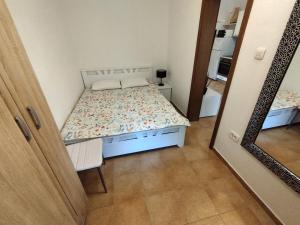 małą sypialnię z łóżkiem i lustrem w obiekcie Apartments Zezelj w miejscowości Sveti Stefan