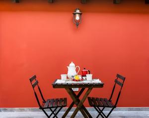 una mesa con tetera y dos sillas contra una pared roja en Cortile in centro - Charm Suite Heart of Lucca en Lucca