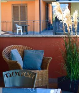 una silla de mimbre con almohadas azules en el patio en Modern apartment with terrace and mezzanine floor, en Colico